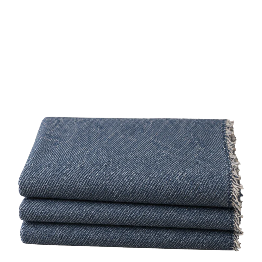 A folded length of new mid-indigo denim with frayed edges.